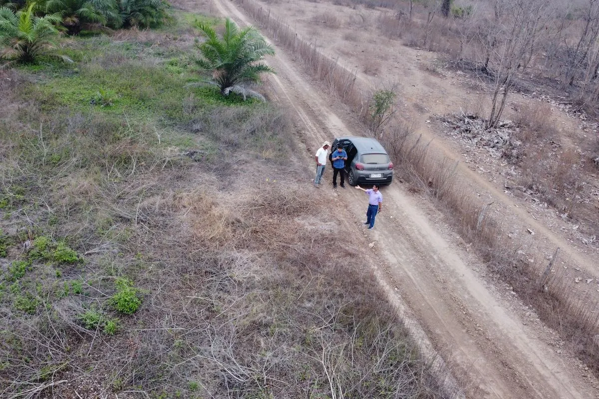 Vista aérea de un vehículo y personas en un camino rural durante una diligencia